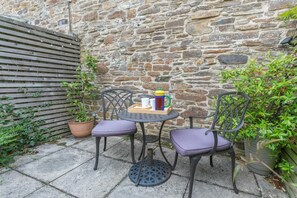 A small outdoor seating area with two chairs and a table, a stone wall, and potted plants. - 1 Bed in Duloe (oc-h27527) (Duloe)