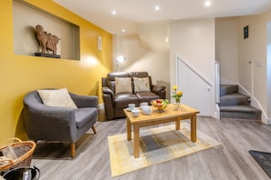 A living room with a sofa, a recliner, a coffee table with fruit, and a staircase. - 1 Bed in Duloe (oc-h27527) (Duloe)