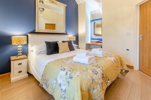 Une chambre à coucher avec un lit, une table de chevet, une lampe et un miroir au-dessus du lit.
