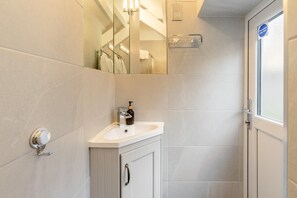 Une salle de bain moderne avec un lavabo blanc, un miroir et un espace douche.