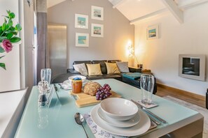 Ein modernes Wohnzimmer mit Essbereich, einer Couch, einem Couchtisch und einer Lampe.