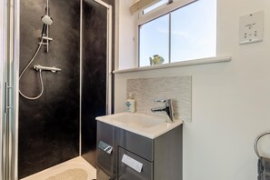 Ein Badezimmer mit Dusche, Waschbecken und Fenster.