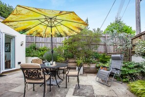 A patio with a table and chairs, a yellow umbrella, and a wooden fence. - 2 Bed in Wells (oc-s41752) (Wells)