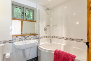 Een badkamer met een wit wastafel, een spiegel, een douche en een bad.