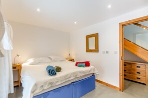 Ein Schlafzimmer mit einem Bett, Nachttischen, einem Spiegel, einem Holzschrank und einer Treppe.