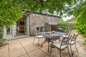 Ein Steinhaus mit Terrasse, Außenbestuhlung und Grillplatz.