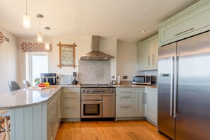 A modern kitchen with a stainless steel refrigerator, a built-in oven, and a microwave. - 4 Bed in Hunstanton (oc-t44905) (Hunstanton)