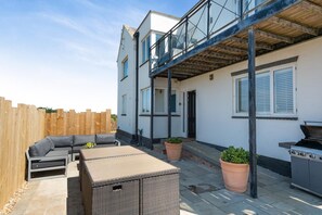 A residential patio with a built-in sofa, a grill, and potted plants. - 4 Bed in Hunstanton (oc-t44905) (Hunstanton)