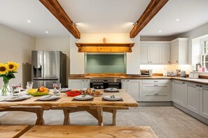 Una cocina moderna con una mesa de madera dispuesta para una comida, un refrigerador y una estufa.
