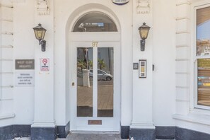 A white building entrance with a glass door marked '97', a no smoking sign, and a security keypad. - 3 Bed in Bournemouth (oc-s44899) (Bournemouth)