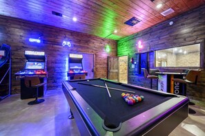 A pool table with colorful balls, arcade machines, and a neon sign. - The Cedarwood Collective · Indoor Pool, Theatre, Putt-Putt & Gameroom | Sleeps 27! (Broken Bow)