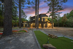 A modern two-story house with a well-maintained lawn and a swing set. - The Cedarwood Collective · Indoor Pool, Theatre, Putt-Putt & Gameroom | Sleeps 27! (Broken Bow)