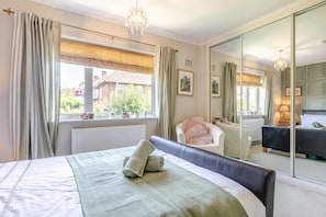 A bedroom with a bed, a chair, a large mirror, and a window with curtains. - 4 Bed in Chesterfield (oc-w45546) (Chesterfield)