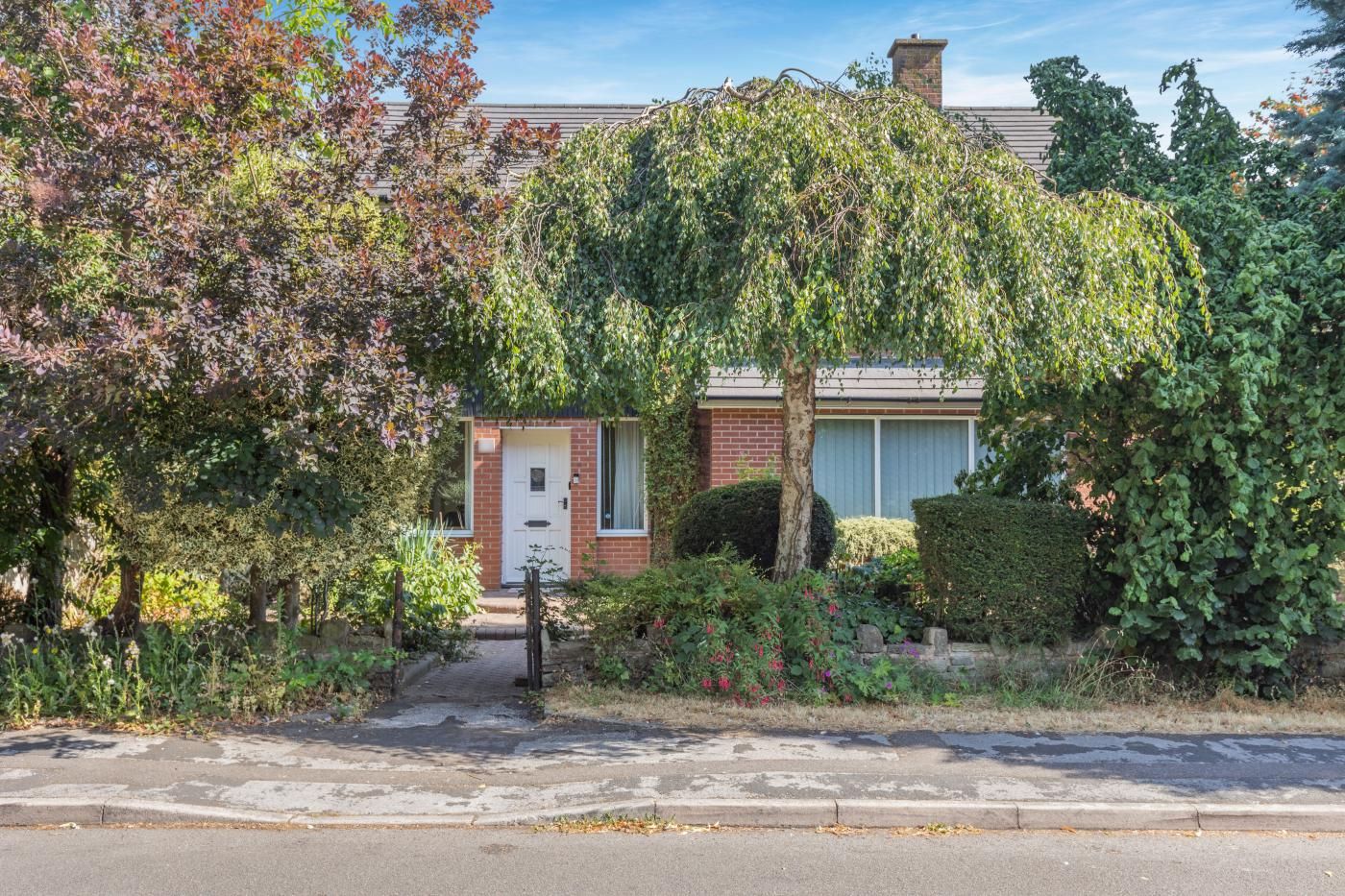 A residential property with a brick house, a front garden, and a pathway leading to the entrance.