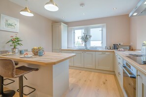 Une cuisine moderne dotée d’un îlot central, de meubles blancs et d’une fenêtre qui laisse entrer la lumière naturelle.