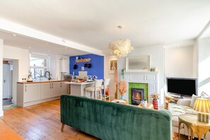 Eine moderne Küche mit weißen Schränken, einer blauen Akzentwand und einem Kamin.