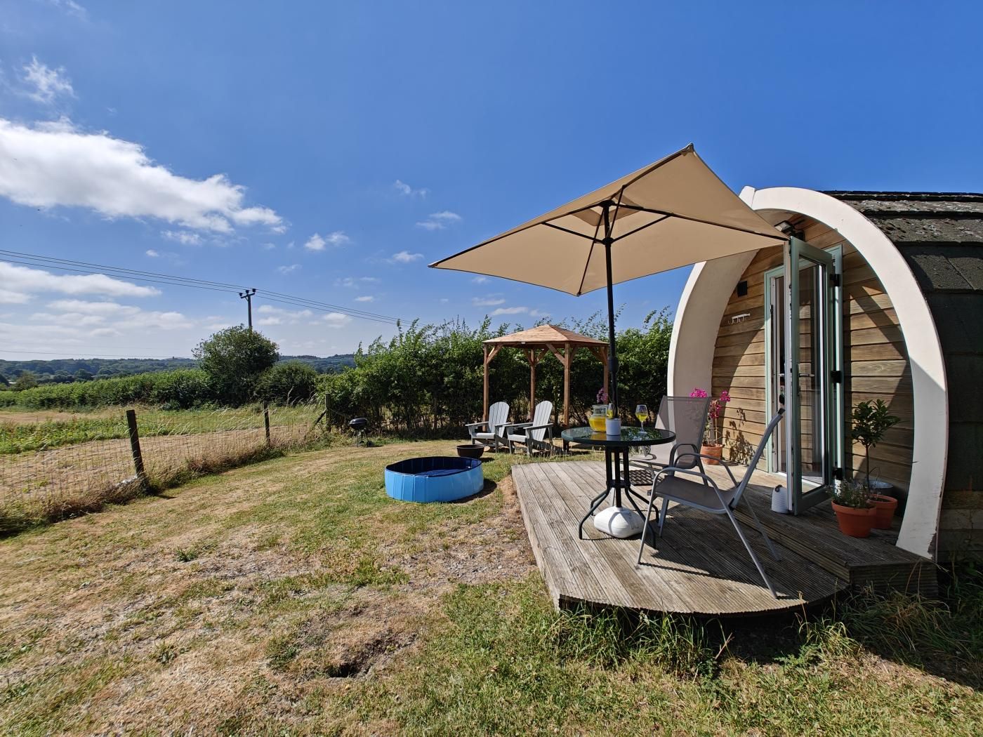 A circular wooden structure with a deck, outdoor seating, and a pergola.