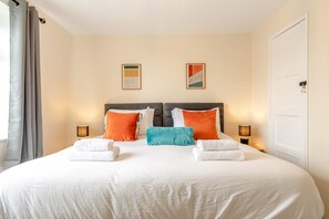 A double bed with white linens, two pillows, and two folded towels. There are two wall-mounted lamps on either side of the bed. - 3 Bed in Leek (oc-l45949) (Leek)