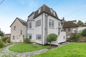 Ein zweistöckiges Haus mit einem Kiesweg, der zur Haustür führt, umgeben von einem gepflegten Rasen und einem kleinen Garten.
