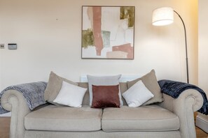 A neutral-toned sofa with three pillows, a floor lamp, and a piece of abstract art on the wall. - 2 Bed in Buxton (oc-p45950) (Buxton)