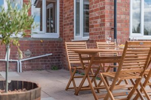 A brick building with a patio area featuring a wooden table and chairs.