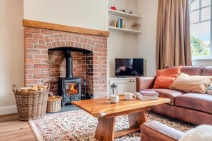 Ein gemütliches Wohnzimmer mit Kamin, Fernseher, Ledersofa und Couchtisch.