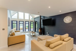 Una sala de estar moderna con un ventanal amplio, una chimenea y un televisor de pantalla plana montado en la pared.