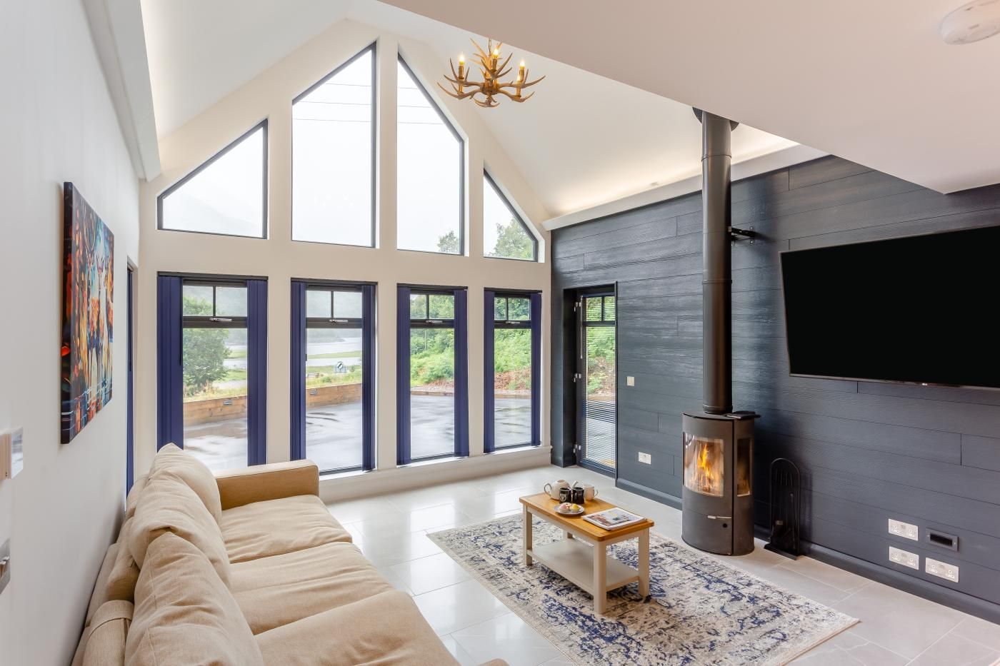 A modern living room with a large sofa, a fireplace, and large windows.