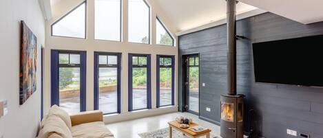 Een moderne woonkamer met een grote bank, een open haard en grote ramen.