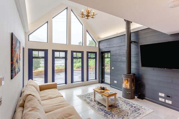 A modern living room with a large sofa, a fireplace, and large windows.