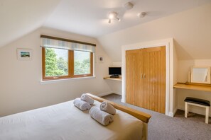 Ein Schlafzimmer mit Bett, Fenster, Kleiderschrank, Schreibtisch und Stuhl.