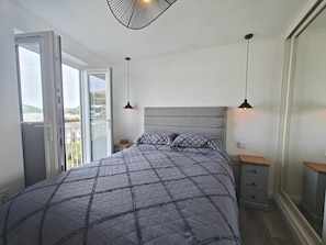 A bedroom with a bed, bedside tables, a window with a view, and pendant lights. - 1 Bed in Kingswear (oc-b45934) (Dartmouth)