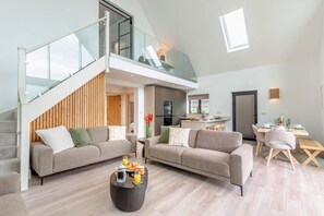 A modern living room with two sofas, a coffee table, and a dining area with a table and chairs. - 3 Bed in Doddington (oc-l45736) (Doddington)