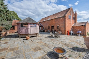 Une cour avec un bâtiment en briques, des sièges en plein air et une structure couverte.