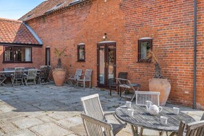 A brick building with a tiled roof, outdoor seating area with chairs and a table, and potted plants. - 8 Bed in Gillingham (oc-w45983) (Gillingham)