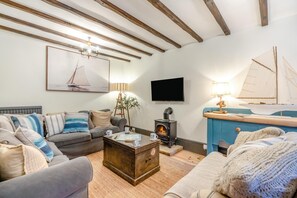 Ein gemütliches Wohnzimmer mit Kamin, Fernseher und maritimer Dekoration.