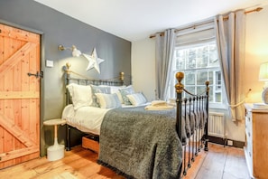 Ein Schlafzimmer mit einem Bett, einer Sterndeko, einer Holztür, einem Fenster mit Vorhängen und einer Lampe.