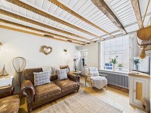 A cozy living room with a brown leather sofa, a wooden coffee table, and a large window with a view of the outside. - 2 Bed in Robin Hoods Bay (oc-o45886) (Robin Hood's Bay)