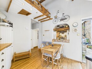 A rustic kitchen with wooden beams, a bicycle decoration, and a dining area with a table and chairs. - 2 Bed in Robin Hoods Bay (oc-o45886) (Robin Hood's Bay)