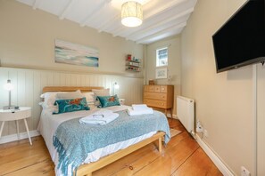A bedroom with a wooden bed, a nightstand, a dresser, a television, and a painting on the wall. - 1 Bed in Robin Hoods Bay (oc-o45887) (Robin Hood's Bay)
