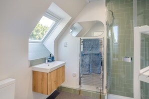 Un baño moderno con tragaluz, ducha y tocador con espejo.