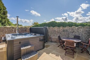 Eine Außenpatio mit Whirlpool, Tisch und Stühlen.