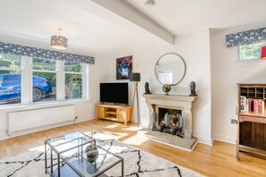Ein geräumiges Wohnzimmer mit Kamin, Fernseher und Bücherregal.