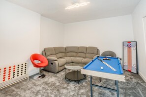 A room with a pool table, a red chair, a sofa, and a curling board. - 4 Bed in East Linton (oc-t45718) (East Linton)