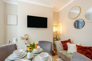 A modern living room with a flat-screen TV, comfortable seating, and a dining area set for four. - 2 Bed in Scarborough (oc-c45973) (Scarborough)