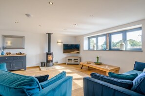 Un salon moderne avec une cheminée, des canapés bleus, une table à manger en bois et une grande fenêtre.
