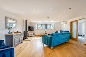 Ein geräumiger Wohnbereich mit Sofa, Fernseher und Kamin.