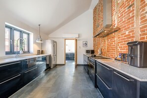 Eine moderne Küche mit Backsteinwand, Edelstahlgeräten und einer großen Kochinsel.
