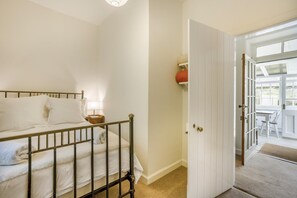 Ein Schlafzimmer mit einem Bett, einem Nachttisch und einer Tür, die auf einen Balkon führt.