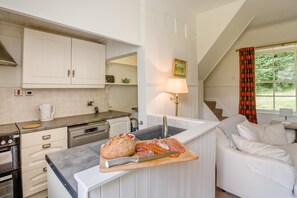 Eine moderne Küche mit weißen Schränken, einem eingebauten Ofen und einer Arbeitsfläche mit einem Brot und Aufschnitt.